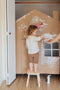 Girl in white shirt painting a cardboard cut-out of a home to symbolise home building 